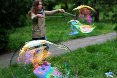 Blurred woman making bubbles in park