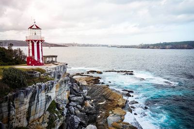 Lighthouse by sea against sky