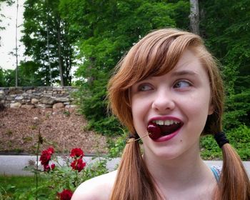 Teenage girl eating cherry at park