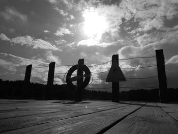 Silhouette of two men on fence against cloudy sky