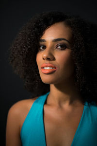 Portrait of smiling young woman against black background