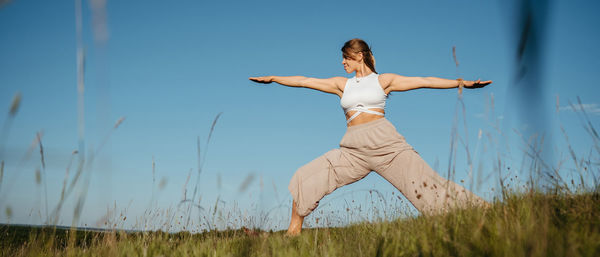 Young adult couple making beautiful pose, man and woman practicing yoga outdoors