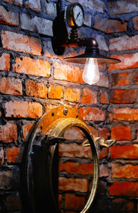 Low angle view of illuminated lamp on brick wall