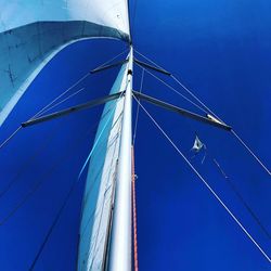 Low angle view of sailboat in sea against blue sky