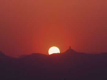 Scenic view of silhouette mountains against orange sky