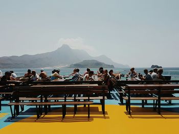 People sitting on cliff by sea