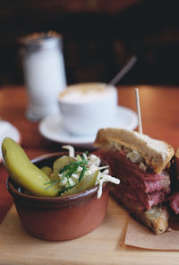 Close-up of pastrami sandwich and pickles on tray