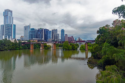 River by city buildings against sky