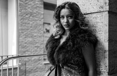 Portrait of confident woman standing against wall