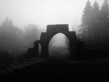 Snow covered cemetery against sky during foggy weather