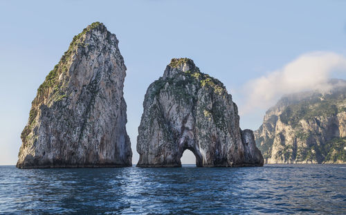 Standing rocks in calm sea against the sky