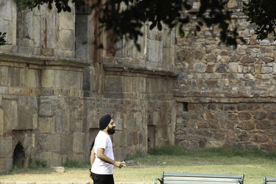 Full length of woman standing against stone wall