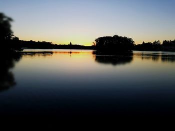 Reflection of trees in calm lake at dusk
