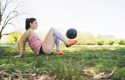 Side view of woman playing ball on field