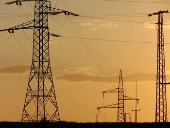 Low angle view of electricity pylon against dramatic sky