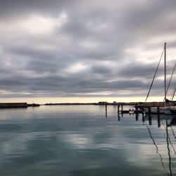 Pier on sea against cloudy sky