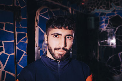 Portrait of illuminated bearded young man in bathroom at bar