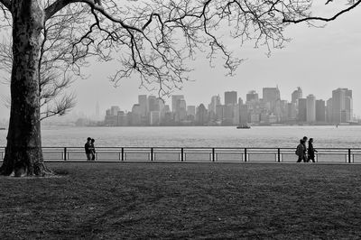 Man and woman standing by river in city against sky