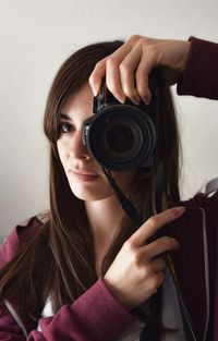 Portrait of beautiful woman photographing with camera at home