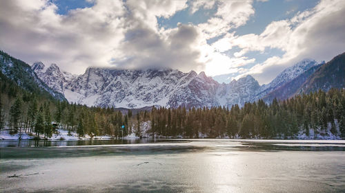 Scenic view of lake by snowcapped mountains against sky