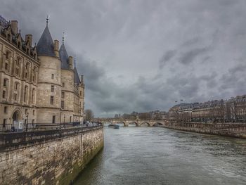 Buildings by river against sky