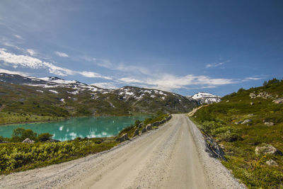 Road amidst snowcapped mountains against sky
