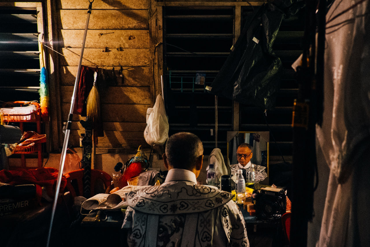 indoors, illuminated, lighting equipment, ceiling, men, religion, place of worship, hanging, spirituality, person, architecture, temple - building, built structure, night, lantern, cultures, retail, electric light