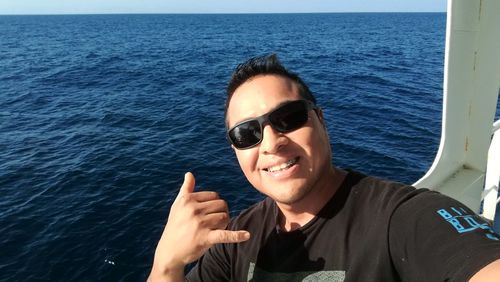 Man gesturing shaka sign in boat at sea
