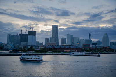 City at waterfront against cloudy sky