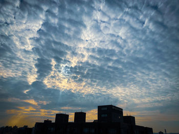 Low angle view of silhouette buildings against dramatic sky