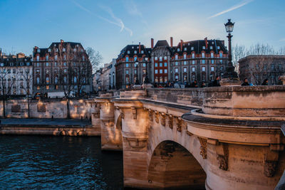 Arch bridge over river against buildings in city