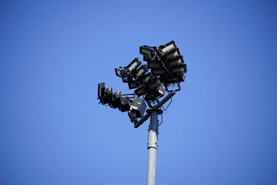 Low angle view of staduim lightning equipment against clear blue sky