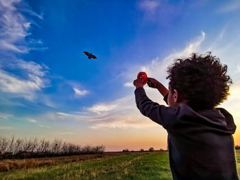 Man holding bird on field against sky