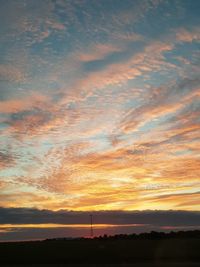 Scenic view of dramatic sky over silhouette landscape during sunset