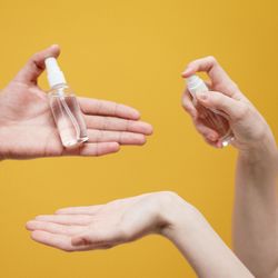 Cropped hands of woman holding pill against blue background