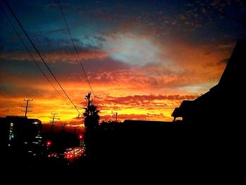 Low angle view of electricity pylon against dramatic sky