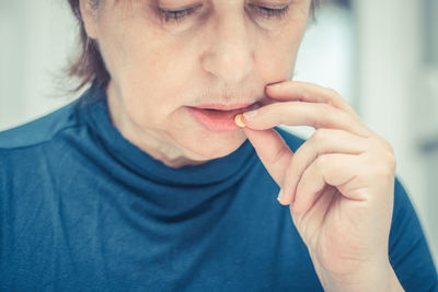 Close-up of woman taking pill at home