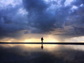 Scenic view of sea against cloudy sky at sunset