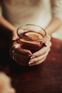 Cropped hand of woman holding coffee on table