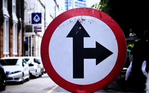 Close-up of arrow sign on road in city