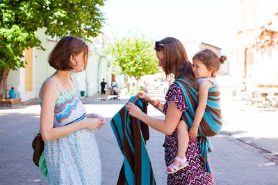 Women standing in town square with city in background