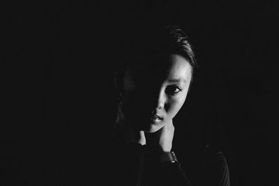 Portrait of young woman against black background