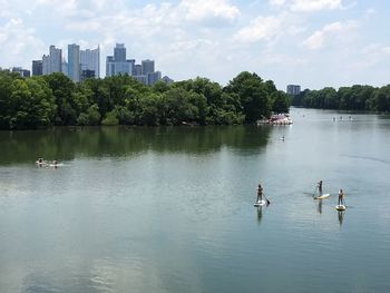 People swimming in river against sky in city