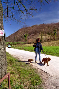 Full length of woman with dog on field against sky