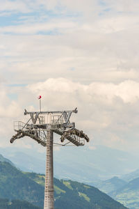 Low angle view of communications tower against cloudy sky