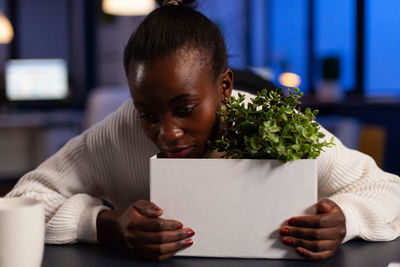 Portrait of woman holding paper while sitting on table