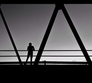 Silhouette man standing on bridge against sky