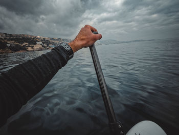 First person point of view of a man paddling on the sup in sea under the cloudy sky