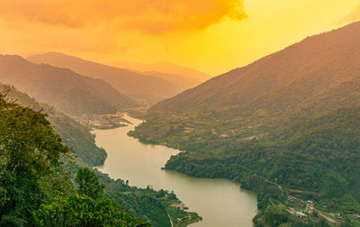 Mountain valley with orange sky and river leading at morning from flat angle