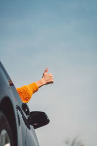 Low angle view of woman holding umbrella against sky